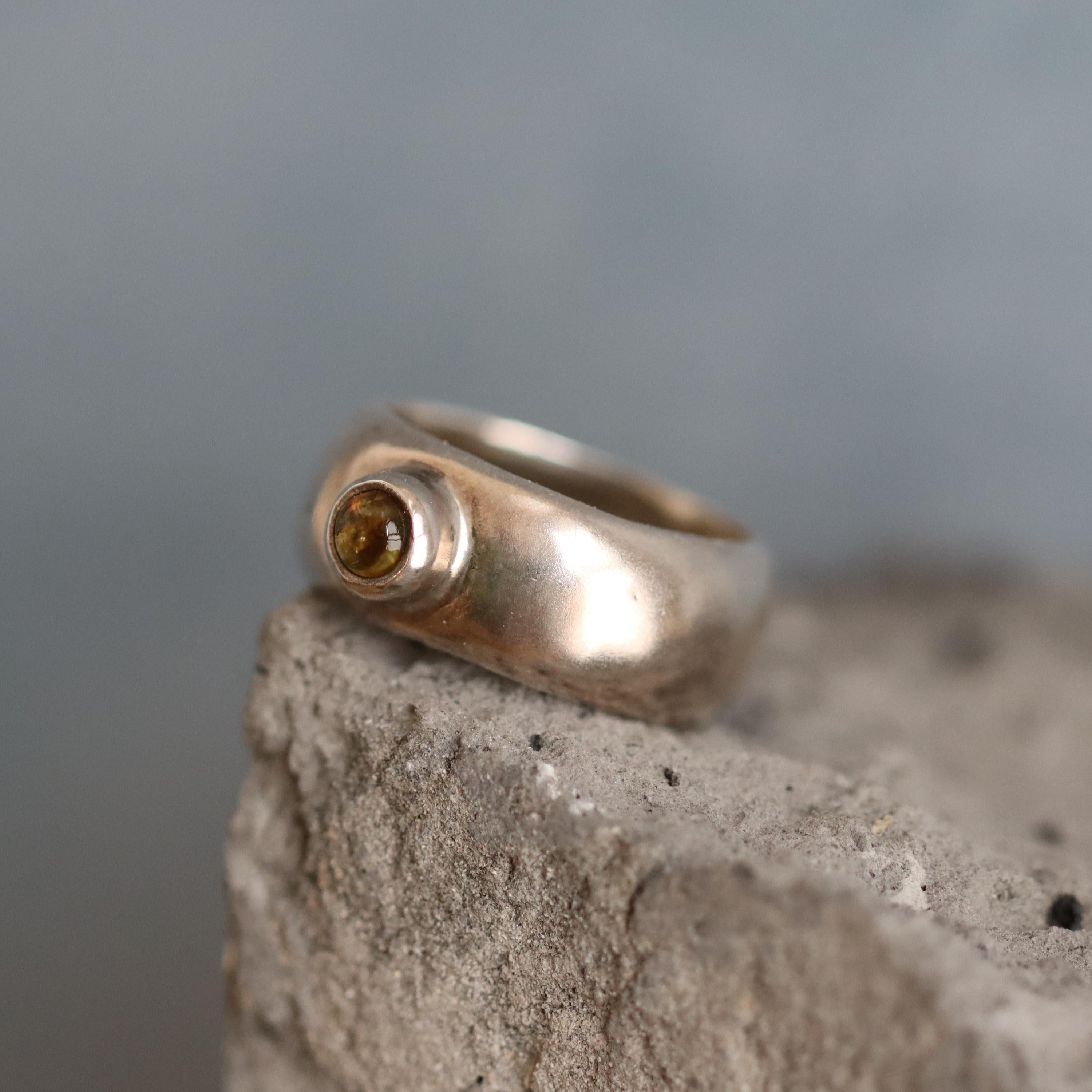 Handmade sterling silver ring featuring a wide dome band and a natural light brown tourmaline gemstone inlay. The polished silver contrasts with the earthy tones of the gemstone, creating a bold yet elegant statement piece. Ideal for everyday wear or gifting, this modern ring blends minimalist design with the grounding energy of tourmaline. A unique and stylish accessory for women who love natural gemstone jewelry.