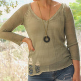 Long necklace featuring a porous black lava stone pendant on an olive green suede strap, perfect for boho and nature-inspired fashion lovers.