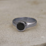 Close-up of artisan silver ring with round faceted onyx in solitaire setting.