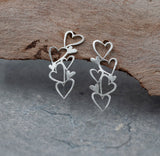 A pair of silver earrings with a cascading design of multiple heart shapes. The earrings are delicate and intricate, with each heart slightly overlapping the next.