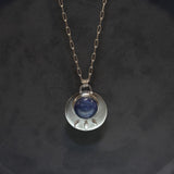 Gift presentation of the kyanite ring and matching pendant in a jewelry box. The bold oval ring and round necklace sit side by side, sterling silver gleaming against a neutral insert. Deep blue gemstones create a cohesive statement set suitable for gifting.