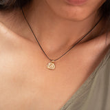 Handmade organic gold pendant necklace on model’s neck. Coin-shaped with a natural textured surface, glowing softly — a timeless nature-inspired treasure.