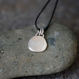 The back of an artisan sterling silver necklace with softly irregular coin pendant, handmade with natural texture and minimalist elegance.