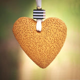 Boho-inspired necklace with a yellow porous lava heart and bold accent bead, hanging from a long white suede cord for a natural, earthy look.