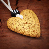 Boho-inspired necklace with a yellow porous lava heart and bold accent bead, hanging from a long white suede cord for a natural, earthy look.