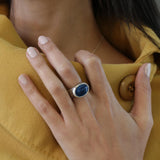 Close-up of the round kyanite pendant necklace in sterling silver. The circular cabochon reveals blue chatoyance and natural texture, set in a sleek bezel on a fine cable chain with a lobster clasp. Minimalist design focuses attention on the gemstone.