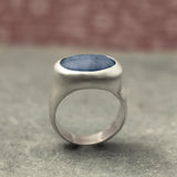 Macro photo highlighting the kyanite gemstones. Linear blue striations and soft internal shimmer are visible in both the oval ring and round pendant. The sterling silver bezels are neatly finished, edges smooth and reflective for a modern, handcrafted feel.