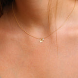 The gold leaf and moonstone birthstone necklace is styled over a simple blouse. The lightweight chain drapes naturally, with the leaf pointing down and the moonstone charm resting beside it, creating a soft botanical accent.