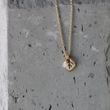 macro of the leaf pendant’s etched veins and polished edges with the moonstone charm catching light. The slim cable chain curves around the pendant; slate backdrop adds a natural, modern feel.