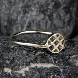 Macro shot of geometric openwork silver ring on textured stone background. The circular lattice form reflects both structure and flow, symbolizing harmony in simplicity.