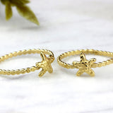 Close-up of a handmade gold starfish rings placed on a white marble surface, showcasing the textured dot band and tiny sea-star charm.