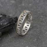 Minimalist silver geometric ring shown standing upright to reveal the repeating pattern.