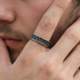 Men’s oxidized silver geometric ring worn on a male model’s hand positioned near the face, highlighting the dark openwork band and modern masculine style.