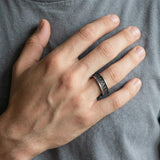 Dark oxidized silver geometric ring worn on a male model’s hand near the chest, capturing the ring’s bold structure and contemporary artisan feel.