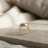 Gold bezel set rose quartz ring photographed standing upright to display the band and setting profile