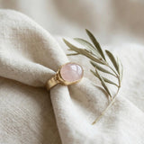 Angled view of the gold statement ring emphasizing the oval pink stone and smooth handcrafted finish