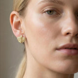 Model wearing small gold leaf stud earrings, natural look with soft light.