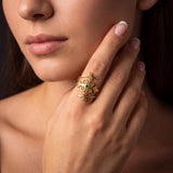 Woman wearing a gold emerald spiral ring with delicate swirl and botanical details, shown in a close-up near her face.