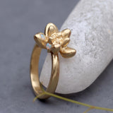 Gold succulent ring with two tiny moonstone accents, shown in a close-up against a white stone with a soft gray background.