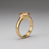 A gold ring with a large oval-shaped gemstone set in the center.