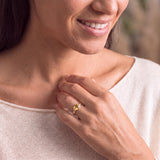 A close-up of a woman's face, showing her hand with a ring on her finger, and a smile on her face.