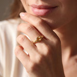 A close-up of a person's hand wearing a gold ring, with their chin resting on their hand.
